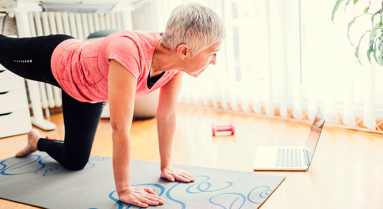 Mature woman doing yoga class at home to improve mental wellbeing